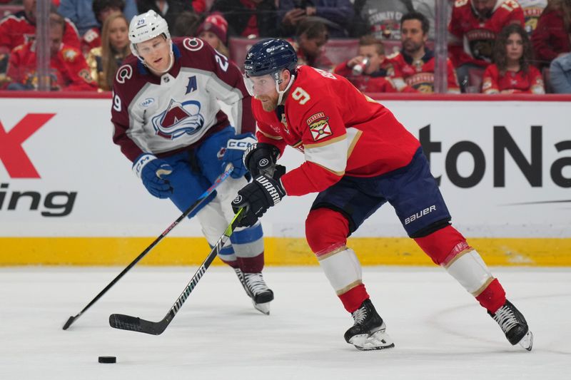 Nov 23, 2024; Sunrise, Florida, USA;  Florida Panthers center Sam Bennett (9) brings the puck up the ice against Colorado Avalanche center Nathan MacKinnon (29) during the first period at Amerant Bank Arena. Mandatory Credit: Jim Rassol-Imagn Images