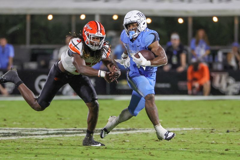 Nov 11, 2023; Orlando, Florida, USA; UCF Knights running back RJ Harvey (7) avoids a tackle by Oklahoma State Cowboys safety Trey Rucker (9) during the second half at FBC Mortgage Stadium. Mandatory Credit: Mike Watters-USA TODAY Sports