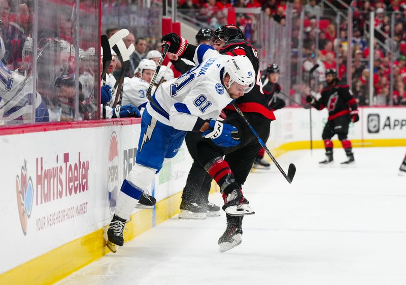 Mar 11, 2025; Raleigh, North Carolina, USA;  Tampa Bay Lightning defenseman Erik Cernak (81) checks Carolina Hurricanes left wing Jordan Martinook (48) during the third period at Lenovo Center. Mandatory Credit: James Guillory-Imagn Images