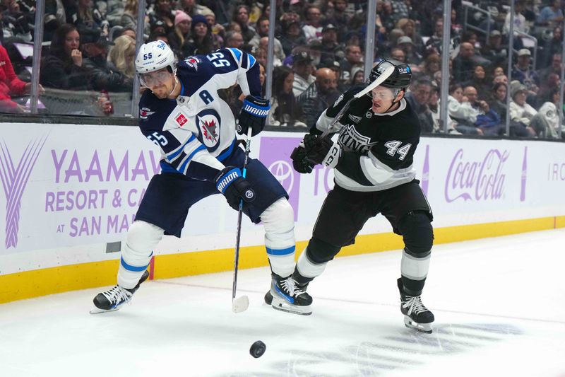 Nov 27, 2024; Los Angeles, California, USA; Winnipeg Jets center Mark Scheifele (55) and LA Kings defenseman Mikey Anderson (44) battle for the puck in the first period at Crypto.com Arena. Mandatory Credit: Kirby Lee-Imagn Images