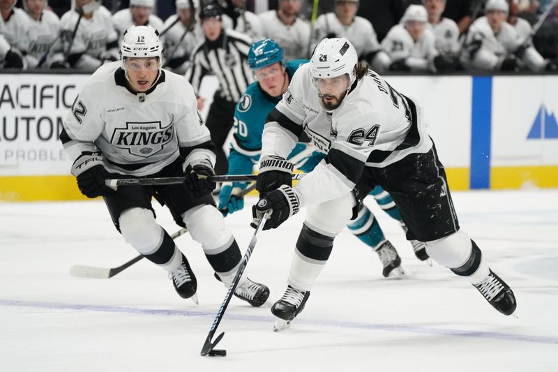 Nov 25, 2024; San Jose, California, USA; Los Angeles Kings center Phillip Danault (24) advances the puck with  left winger Trevor Moore past San Jose Sharks left wing Fabian Zetterlund (20)  in the first period at SAP Center at San Jose. Mandatory Credit: David Gonzales-Imagn Images