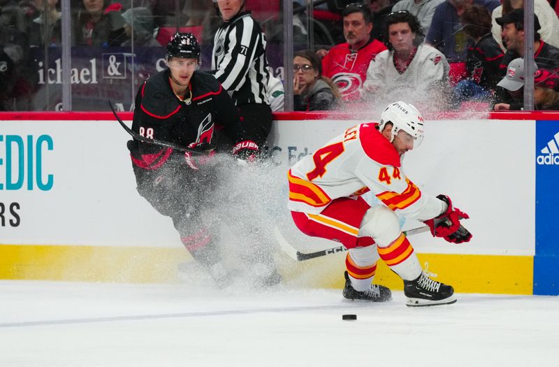 Mar 10, 2024; Raleigh, North Carolina, USA;  Carolina Hurricanes center Martin Necas (88) chips the puck away from Calgary Flames defensemen Joel Hanley (44) during the third period at PNC Arena. Mandatory Credit: James Guillory-USA TODAY Sports