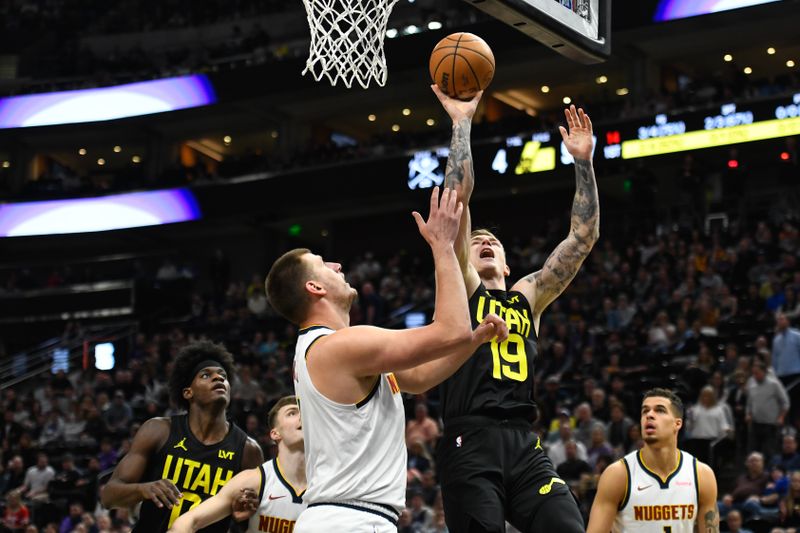 SALT LAKE CITY, UTAH - APRIL 09: Luka Samanic #19 of the Utah Jazz lays up a shot against Nikola Jokic #15 of the Denver Nuggets during the first half at Delta Center on April 09, 2024 in Salt Lake City, Utah. NOTE TO USER: User expressly acknowledges and agrees that, by downloading and or using this photograph, User is consenting to the terms and conditions of the Getty Images License Agreement.  (Photo by Alex Goodlett/Getty Images)