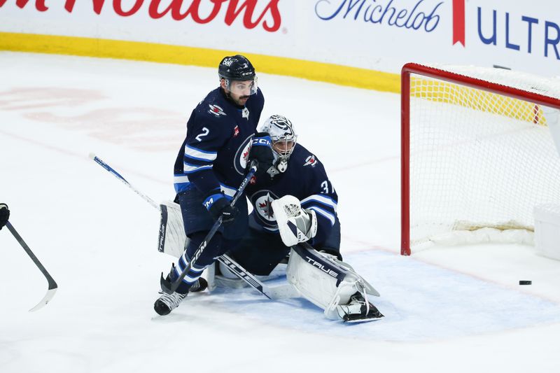 Nov 30, 2023; Winnipeg, Manitoba, CAN; Winnipeg Jets goalie Connor Hellebuyck (37) and Winnipeg Jets defenseman Dylan DeMelo (2) watch an Edmonton Oilers shot go wide if the net during the third period at Canada Life Centre. Mandatory Credit: Terrence Lee-USA TODAY Sports