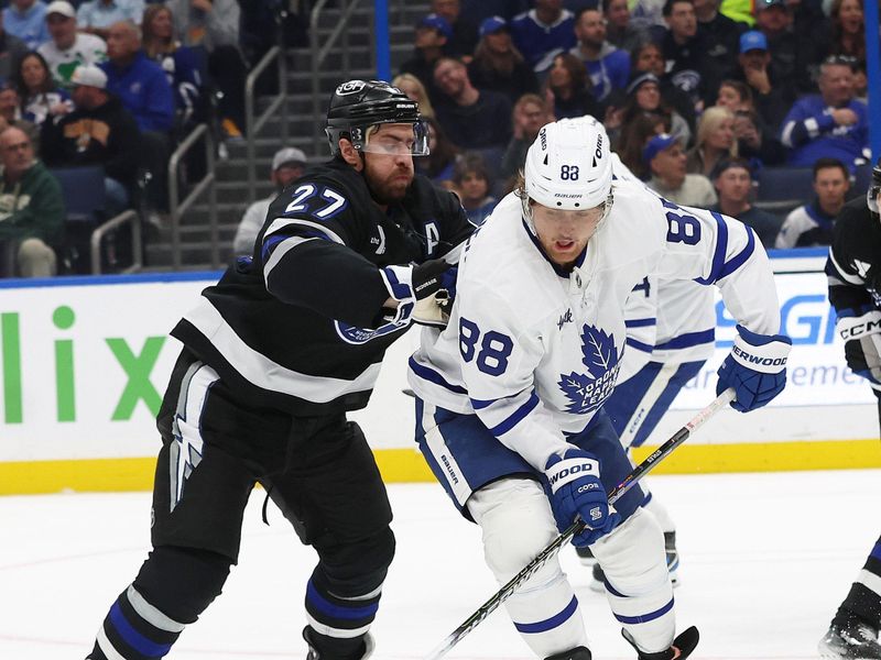 Nov 30, 2024; Tampa, Florida, USA; Tampa Bay Lightning defenseman Victor Hedman (77) and Toronto Maple Leafs right wing William Nylander (88) defend to control the puck during the third period at Amalie Arena. Mandatory Credit: Kim Klement Neitzel-Imagn Images