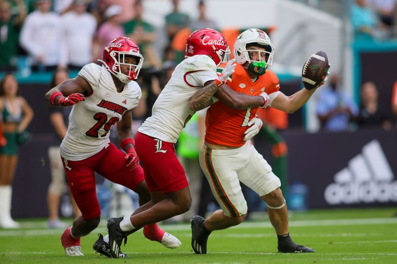 Nov 18, 2023; Miami Gardens, Florida, USA; Miami Hurricanes wide receiver Xavier Restrepo (7) is tackled short of the end zone by Louisville Cardinals defensive back Quincy Riley (3) during the fourth quarter at Hard Rock Stadium. Mandatory Credit: Sam Navarro-USA TODAY Sports