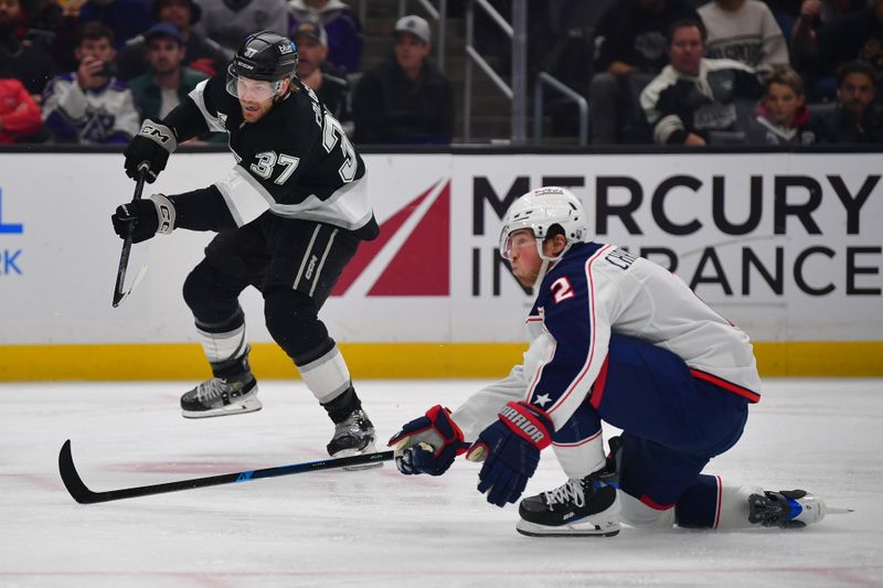 Dec 22, 2025; Los Angeles, California, USA; Los Angeles Kings left wing Warren Foegele (37) shoots against the defense of Columbus Blue Jackets defenseman Jake Christiansen (2) during the second period at Crypto.com Arena. Mandatory Credit: Gary A. Vasquez-Imagn Images