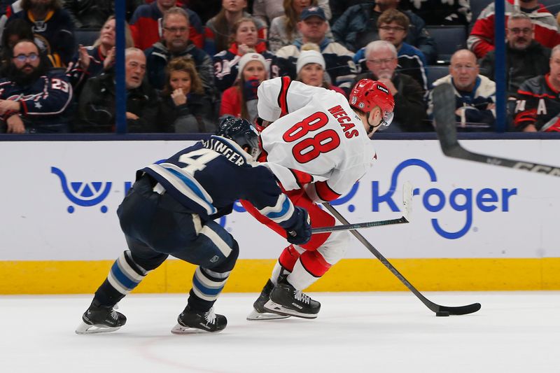 Dec 31, 2024; Columbus, Ohio, USA; Carolina Hurricanes center Martin Necas (88) skates around the check of Columbus Blue Jackets center Cole Sillinger (4) during overtime at Nationwide Arena. Mandatory Credit: Russell LaBounty-Imagn Images