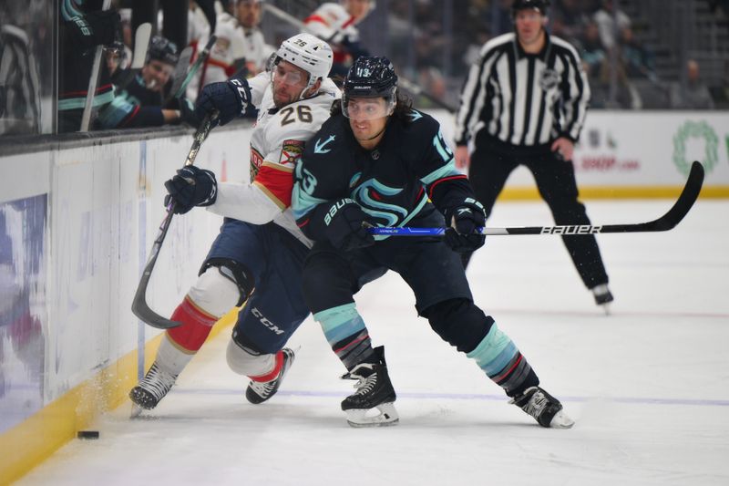 Dec 12, 2023; Seattle, Washington, USA; Florida Panthers defenseman Uvis Balinskis (26) and Seattle Kraken left wing Brandon Tanev (13) play the puck off the wall during the first period at Climate Pledge Arena. Mandatory Credit: Steven Bisig-USA TODAY Sports.