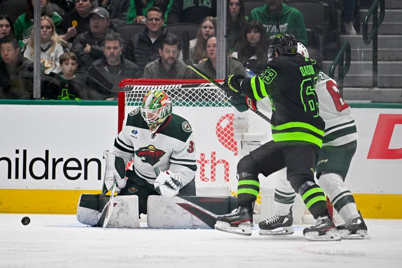 Jan 10, 2024; Dallas, Texas, USA; Minnesota Wild goaltender Jesper Wallstedt (30) makes a save as Dallas Stars right wing Evgenii Dadonov (63) looks for the rebound during the first period at the American Airlines Center. Mandatory Credit: Jerome Miron-USA TODAY Sports