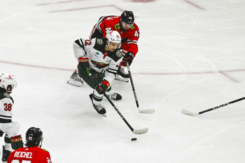 Apr 7, 2024; Chicago, Illinois, USA;  Chicago Blackhawks center Colin Blackwell (43) and Minnesota Wild center Marat Khusnutdinov (22) chase the puck during the first period at the United Center. Mandatory Credit: Matt Marton-USA TODAY Sports