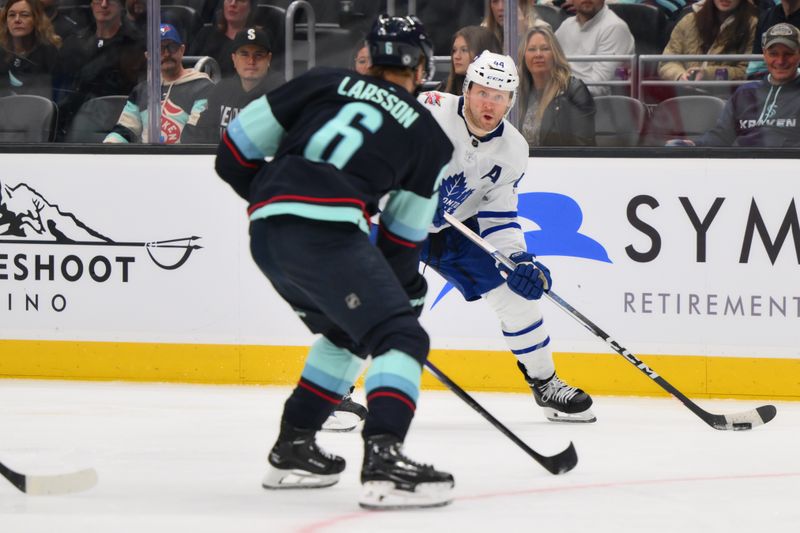 Jan 21, 2024; Seattle, Washington, USA; Toronto Maple Leafs defenseman Morgan Rielly (44) looks to pass the puck while defended by Seattle Kraken defenseman Adam Larsson (6) during the third period at Climate Pledge Arena. Mandatory Credit: Steven Bisig-USA TODAY Sports