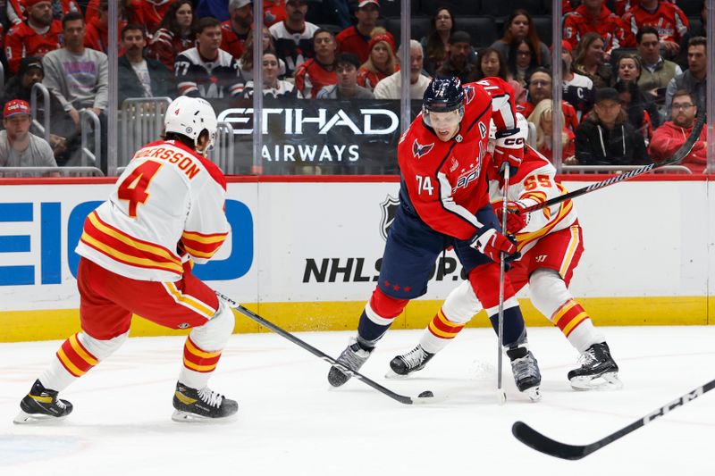 Oct 16, 2023; Washington, District of Columbia, USA; Washington Capitals defenseman John Carlson (74) prepares to shoot the puck as Calgary Flames defenseman Noah Hanifin (55) and Flames defenseman Rasmus Andersson (4) defend in the first period at Capital One Arena. Mandatory Credit: Geoff Burke-USA TODAY Sports