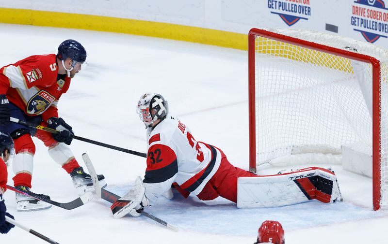 Dec 19, 2025; Sunrise, Florida, USA;  Carolina Hurricanes goaltender Brandon Bussi (32) blocks a shot by Florida Panthers center Sam Bennett (9) during the second period at Amerant Bank Arena. Mandatory Credit: Rhona Wise-Imagn Images