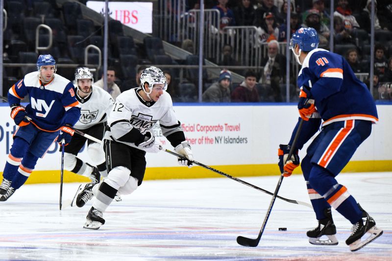 Dec 9, 2023; Elmont, New York, USA; Los Angeles Kings left wing Trevor Moore (12) skates with the puck while being defended by New York Islanders defenseman Robert Bortuzzo (41) during the first period at UBS Arena. Mandatory Credit: John Jones-USA TODAY Sports