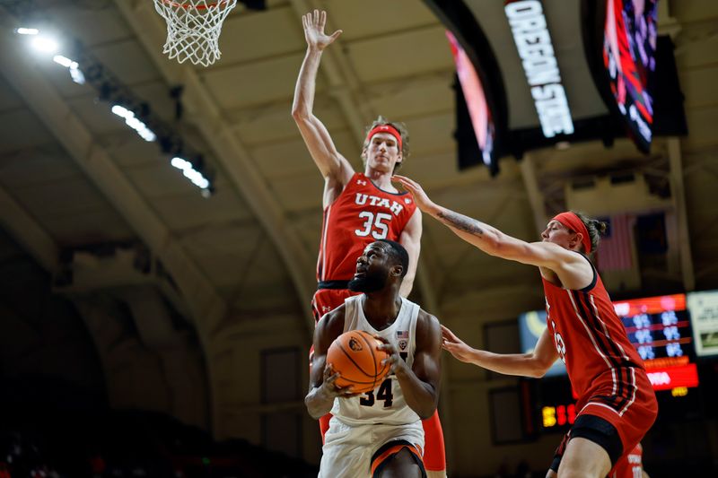 Jan 26, 2023; Corvallis, Oregon, USA; Oregon State Beavers forward Rodrigue Andela (34) attempts to score as Utah Utes center Branden Carlson (35) and Utah Utes guard Gabe Madsen (55, right) defend during the first half at Gill Coliseum. Mandatory Credit: Soobum Im-USA TODAY Sports