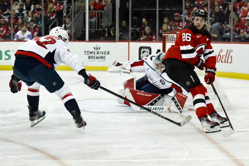 Oct 19, 2024; Newark, New Jersey, USA; New Jersey Devils center Jack Hughes (86) passes the puck as Washington Capitals defenseman Martin Fehervary (42) and Washington Capitals goaltender Logan Thompson (48) defend during the second period at Prudential Center. Mandatory Credit: John Jones-Imagn Images