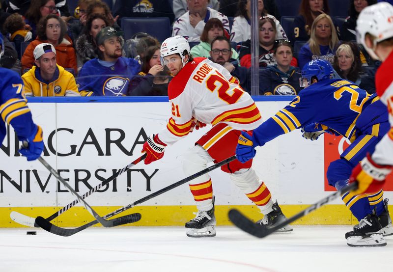 Nov 9, 2024; Buffalo, New York, USA;  Calgary Flames center Kevin Rooney (21) looks to make a pass as Buffalo Sabres right wing Jack Quinn (22) defends during the first period at KeyBank Center. Mandatory Credit: Timothy T. Ludwig-Imagn Images