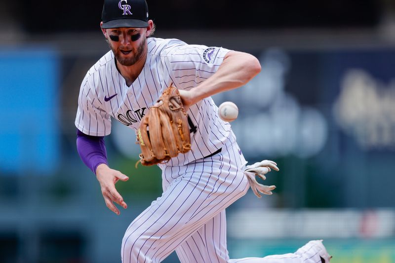 Jun 23, 2024; Denver, Colorado, USA; Colorado Rockies third baseman Ryan McMahon (24) bobbles the ball in the sixth inning against the Washington Nationals at Coors Field. Mandatory Credit: Isaiah J. Downing-USA TODAY Sports