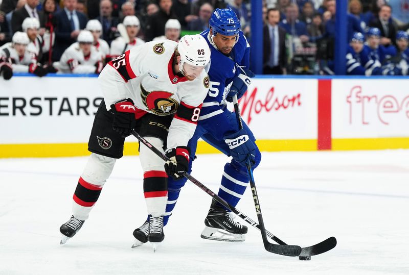 Nov 12, 2024; Toronto, Ontario, CAN; Ottawa Senators defenseman Jake Sanderson (85) battles for the puck with Toronto Maple Leafs right wing Ryan Reaves (75) during the first period at Scotiabank Arena. Mandatory Credit: Nick Turchiaro-Imagn Images