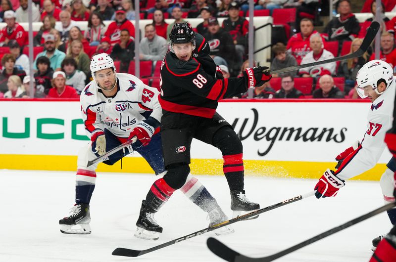 Nov 3, 2024; Raleigh, North Carolina, USA;  Carolina Hurricanes center Martin Necas (88) gets the shot away against Washington Capitals right wing Tom Wilson (43) during the first period at Lenovo Center. Mandatory Credit: James Guillory-Imagn Images