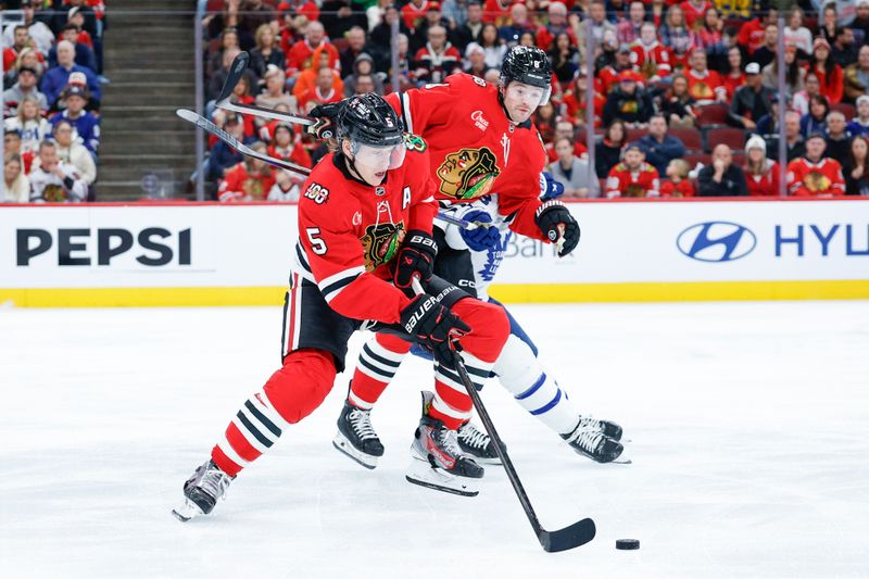 Nov 15, 2025; Chicago, Illinois, USA; Chicago Blackhawks defenseman Connor Murphy (5) tries to control the puck against the Toronto Maple Leafs during the first period at United Center. Mandatory Credit: Kamil Krzaczynski-Imagn Images