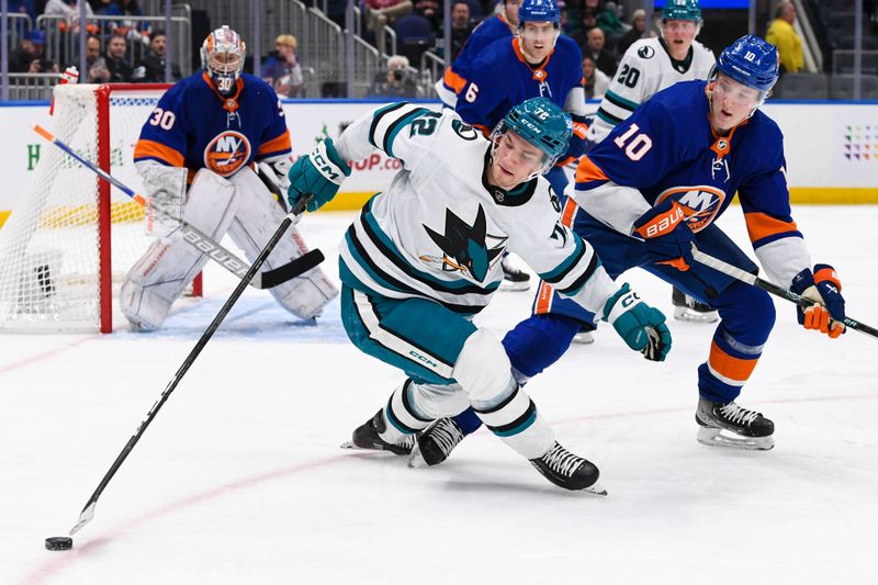 Dec 5, 2023; Elmont, New York, USA; San Jose Sharks left wing William Eklund (72) attempts to control the puck defended by New York Islanders right wing Simon Holmstrom (10) during the third period at UBS Arena. Mandatory Credit: Dennis Schneidler-USA TODAY Sports