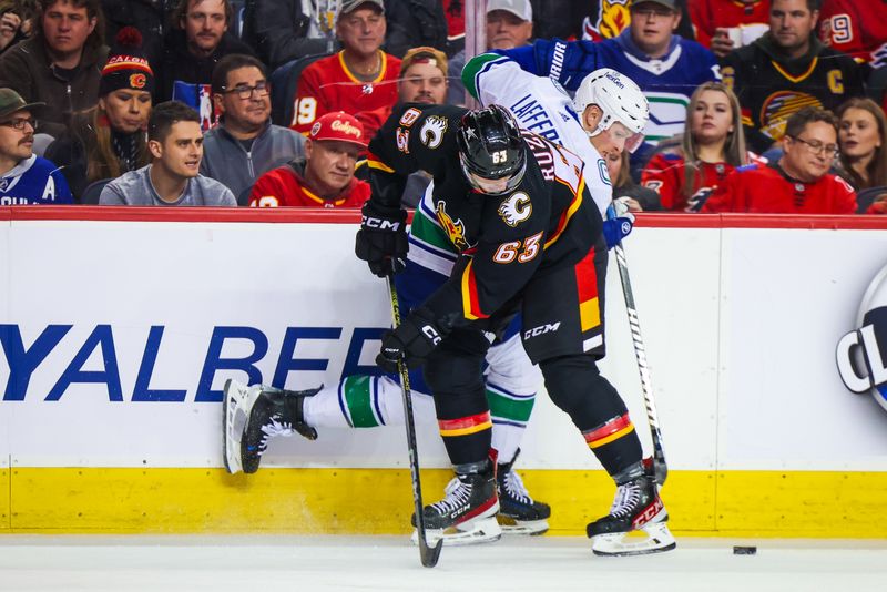 Dec 2, 2023; Calgary, Alberta, CAN; Calgary Flames center Adam Ruzicka (63) and Vancouver Canucks center Sam Lafferty (18) battle for the puck during the second period at Scotiabank Saddledome. Mandatory Credit: Sergei Belski-USA TODAY Sports