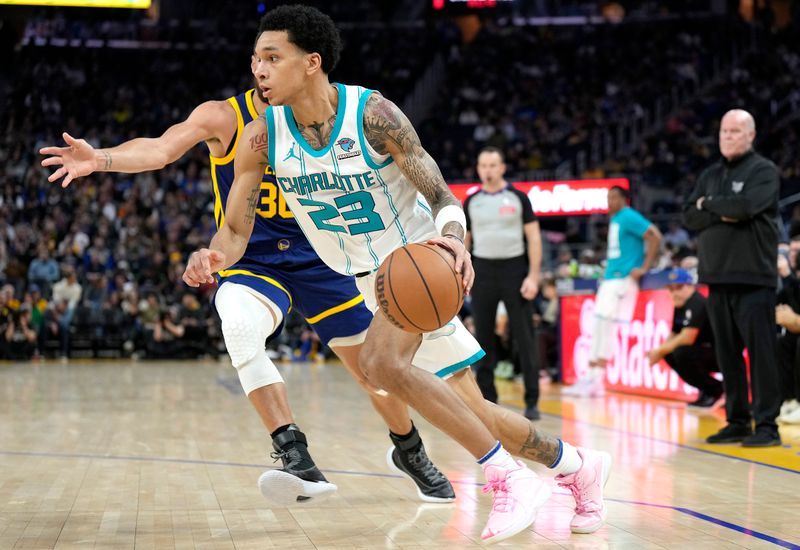 SAN FRANCISCO, CALIFORNIA - FEBRUARY 23: Tre Mann #23 of the Charlotte Hornets dribbling the ball past Stephen Curry #30 of the Golden State Warriors during the third quarter of an NBA basketball game at Chase Center on February 23, 2024 in San Francisco, California. NOTE TO USER: User expressly acknowledges and agrees that, by downloading and or using this photograph, User is consenting to the terms and conditions of the Getty Images License Agreement. (Photo by Thearon W. Henderson/Getty Images)