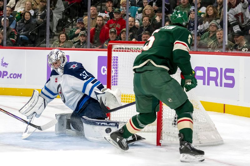 Nov 25, 2024; Saint Paul, Minnesota, USA;  Winnipeg Jets goalie Connor Hellebuyck (37) stops Minnesota Wild defenseman Jacob Middleton (5) on a breakaway during the second period at Xcel Energy Center. Mandatory Credit: Nick Wosika-Imagn Images