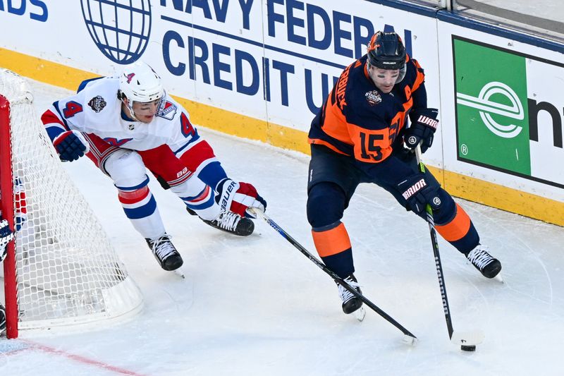 Feb 18, 2024; East Rutherford, New Jersey, USA;  New York Islanders right wing Cal Clutterbuck (15) skates with the puck defended by New York Rangers defenseman Braden Schneider (4) during the first period in a Stadium Series ice hockey game at MetLife Stadium. Mandatory Credit: Dennis Schneidler-USA TODAY Sports