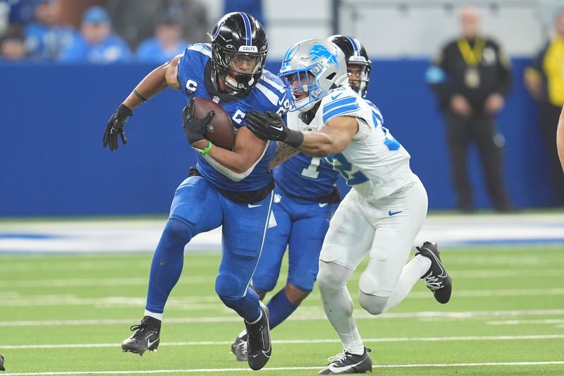 Indianapolis Colts running back Evan Hull (26) tries pulling away from Detroit Lions safety Brian Branch (32) during the second half of an NFL football game, Sunday, Nov. 24, 2024, in Indianapolis. (AP Photo/Michael Conroy)