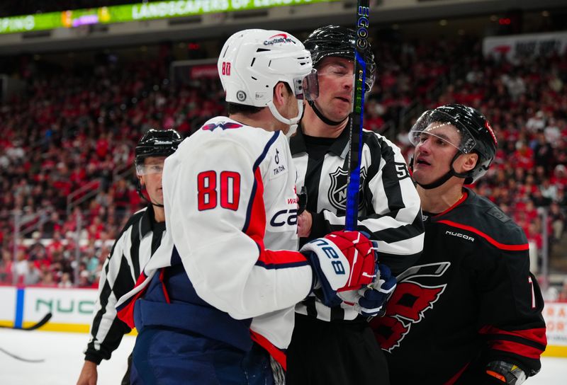 Nov 3, 2024; Raleigh, North Carolina, USA;  Washington Capitals left wing Pierre-Luc Dubois (80) and Carolina Hurricanes defenseman Dmitry Orlov (7) have words during the second period at Lenovo Center. Mandatory Credit: James Guillory-Imagn Images