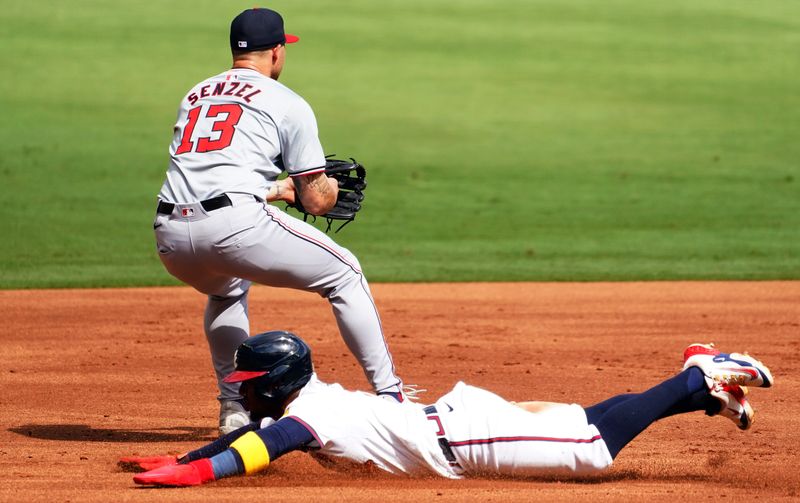 May 27, 2024; Cumberland, Georgia, USA; Atlanta Braves second baseman Ozzie Albies (1) slides into third base against Washington Nationals third baseman Nick Senzel (13) during the first inning at Truist Park. Mandatory Credit: John David Mercer-USA TODAY Sports