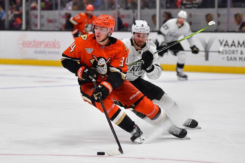 Nov 29, 2024; Anaheim, California, USA; Anaheim Ducks defenseman Pavel Mintyukov (34) moves the puck ahead of Los Angeles Kings right wing Adrian Kempe (9) during the third period at Honda Center. Mandatory Credit: Gary A. Vasquez-Imagn Images