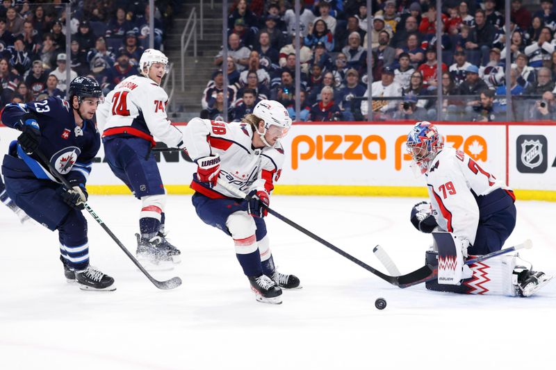 Mar 11, 2024; Winnipeg, Manitoba, CAN; Washington Capitals defenseman Rasmus Sandin (38) skates with the puck past Winnipeg Jets center Sean Monahan (23) in front of Washington Capitals goaltender Charlie Lindgren (79) in the second period at Canada Life Centre. Mandatory Credit: James Carey Lauder-USA TODAY Sports