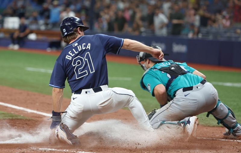 Jun 24, 2024; St. Petersburg, Florida, USA;  Tampa Bay Rays outfielder Jonny DeLuca (21) scores a run as Seattle Mariners catcher Cal Raleigh (29) attempted to tag him out during the eighth inning at Tropicana Field. Mandatory Credit: Kim Klement Neitzel-USA TODAY Sports