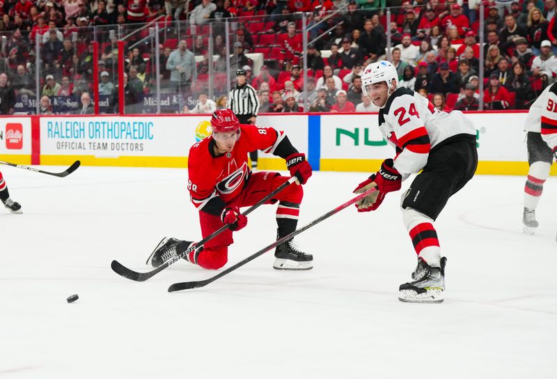 Oct 15, 2024; Raleigh, North Carolina, USA;  Carolina Hurricanes center Martin Necas (88) shot is blocked by New Jersey Devils defenseman Seamus Casey (24) during the third period at PNC Arena. Mandatory Credit: James Guillory-Imagn Images