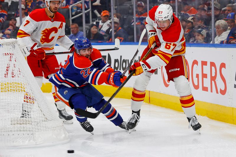 Sep 21, 2025; Edmonton, Alberta, CAN; Calgary Flames defensemen Axel Hurtig (67) and Edmonton Oilers Forward Matt Savoie (22) battle for a loose puck during the third period at Rogers Place. Mandatory Credit: Perry Nelson-Imagn Images