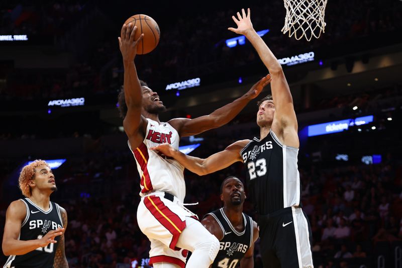 MIAMI, FLORIDA - OCTOBER 15: Jimmy Butler #22 of the Miami Heat drives against Zach Collins #23 of the San Antonio Spurs during the second quarter of a preseason game at Kaseya Center on October 15, 2024 in Miami, Florida. NOTE TO USER: User expressly acknowledges and agrees that, by downloading and or using this photograph, User is consenting to the terms and conditions of the Getty Images License Agreement. (Photo by Megan Briggs/Getty Images)