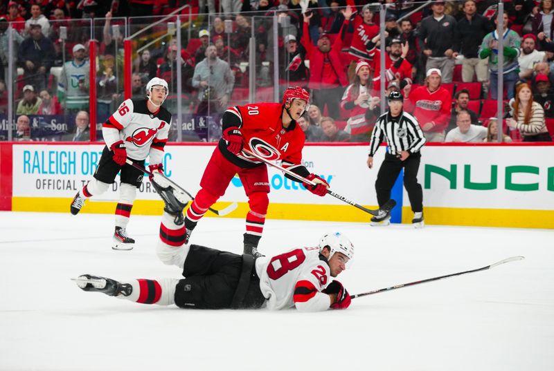 Oct 15, 2024; Raleigh, North Carolina, USA;  Carolina Hurricanes center Sebastian Aho (20) scores an empty net goal past New Jersey Devils right wing Timo Meier (28) during the third period at PNC Arena. Mandatory Credit: James Guillory-Imagn Images