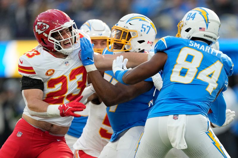 Kansas City Chiefs linebacker Drue Tranquill (23) defends against Los Angeles Chargers linebacker Amen Ogbongbemiga (57) and tight end Stone Smartt (84) during an NFL football game Monday, Jan. 8, 2024, in Inglewood, Calif. (AP Photo/Ashley Landis)