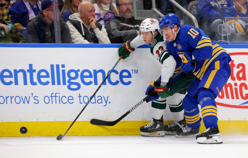 Nov 10, 2023; Buffalo, New York, USA;  Minnesota Wild center Marco Rossi (23) and Buffalo Sabres defenseman Henri Jokiharju (10) go after a loose puck along the boards during the third period at KeyBank Center. Mandatory Credit: Timothy T. Ludwig-USA TODAY Sports