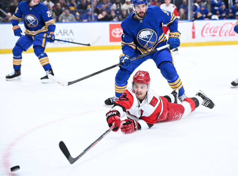 Nov 23, 2025; Buffalo, New York, USA; Carolina Hurricanes center Sebastian Aho (20) reaches for the puck in front of Buffalo Sabres defenseman Conor Timmins (21)in the first period at KeyBank Center. Mandatory Credit: Mark Konezny-Imagn Images