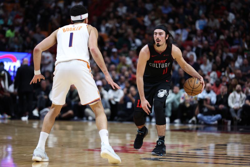 MIAMI, FLORIDA - JANUARY 29: Jaime Jaquez Jr. #11 of the Miami Heat dribbles the ball against Devin Booker #1 of the Phoenix Suns during the third quarter of the game at Kaseya Center on January 29, 2024 in Miami, Florida. NOTE TO USER: User expressly acknowledges and agrees that, by downloading and or using this photograph, User is consenting to the terms and conditions of the Getty Images License Agreement. (Photo by Megan Briggs/Getty Images)