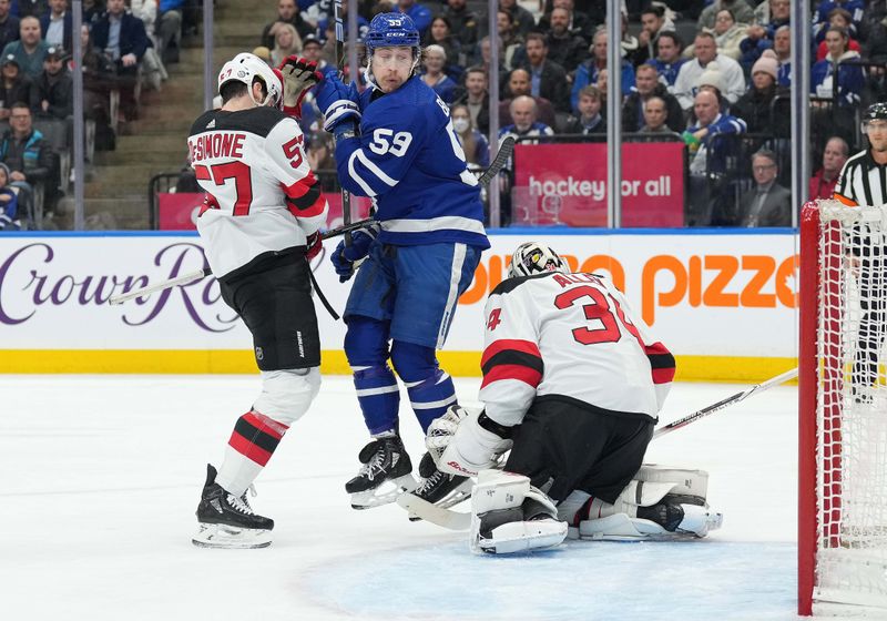 Mar 26, 2024; Toronto, Ontario, CAN; Toronto Maple Leafs left wing Tyler Bertuzzi (59) battles for the puck with New Jersey Devils defenseman Nick DeSimone (57) in front of  goaltender Jake Allen (34) during the first period at Scotiabank Arena. Mandatory Credit: Nick Turchiaro-USA TODAY Sports