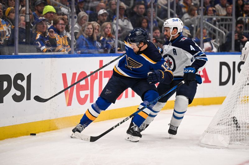 May 2, 2025; St. Louis, Missouri, USA; St. Louis Blues right wing Alexey Toropchenko (13) and Winnipeg Jets defenseman Neal Pionk (4) battle for the puck during the second period in game six of the first round of the 2025 Stanley Cup Playoffs at Enterprise Center. Mandatory Credit: Connor Hamilton-Imagn Images