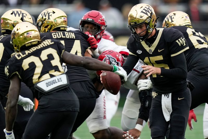 Nov 11, 2023; Winston-Salem, North Carolina, USA; Wake Forest Demon Deacons quarterback Michael Kern (15) fakes a handoff to running back Demond Claiborne (23) during the second half against the North Carolina State Wolfpack at Allegacy Federal Credit Union Stadium. Mandatory Credit: Jim Dedmon-USA TODAY Sports