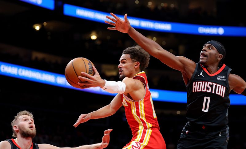 ATLANTA, GEORGIA - FEBRUARY 10:  Trae Young #11 of the Atlanta Hawks drives against Jock Landale #2 and Aaron Holiday #0 of the Houston Rockets during the first quarter at State Farm Arena on February 10, 2024 in Atlanta, Georgia.  NOTE TO USER: User expressly acknowledges and agrees that, by downloading and/or using this photograph, user is consenting to the terms and conditions of the Getty Images License Agreement.  (Photo by Kevin C. Cox/Getty Images)