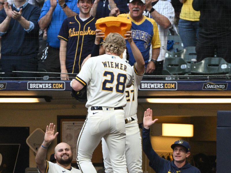 May 23, 2023; Milwaukee, Wisconsin, USA; Milwaukee Brewers right fielder Joey Wiemer (28) is crowned with a cheese head by Milwaukee Brewers shortstop Willy Adames (27) after hitting a home run against the Houston Astros in the third inning at American Family Field. Mandatory Credit: Michael McLoone-USA TODAY Sports